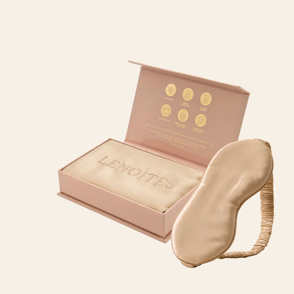 Pillowcase and Sleep Mask in Mulberry Silk by Lenoites featuring a beige silk sleep mask and a beige mulberry silk pillowcase presented in an open blush pink box against a soft light background.