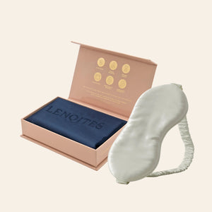Pillowcase and Sleep Mask in Mulberry Silk by Lenoites featuring a grey silk sleep mask and a blue mulberry silk pillowcase presented in an open blush pink box against a soft light background.