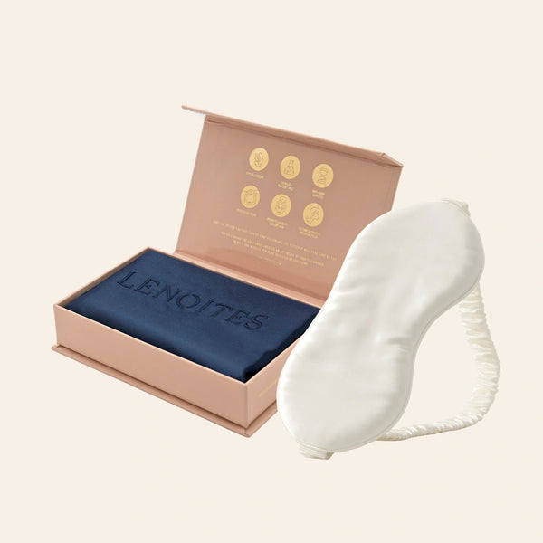 Pillowcase and Sleep Mask in Mulberry Silk by Lenoites featuring a white silk sleep mask and a blue mulberry silk pillowcase presented in an open blush pink box against a soft light background.