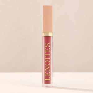 Tinted Lip Oil in Clever by Lenoites, featuring a sleek tube with a pink cap and clear body, showcasing the darker pink tint, displayed against a soft beige background.