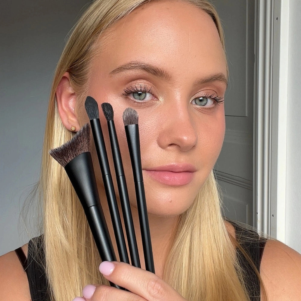 Brush Collection by Lenoites featuring four elegant makeup brushes with black handles and soft bristles, displayed against a soft beige background.