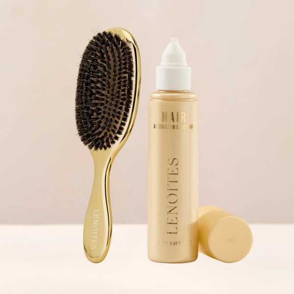 The Hair Growth Duo by Lenoites featuring a gold hairbrush and the Hair Growth Serum in a transparent bottle with a golden tone, styled against a soft light beige background.