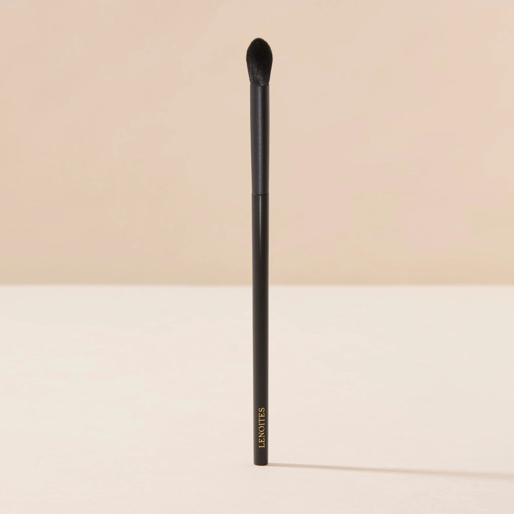 Brush Me Tapered Blender Brush No. 102 by Lenoites, featuring a black handle and a tapered brush head, displayed against a soft beige background.