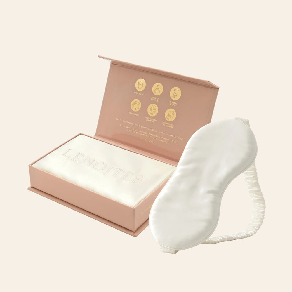 Pillowcase and Sleep Mask in Mulberry Silk by Lenoites featuring a white silk sleep mask and a white mulberry silk pillowcase presented in an open blush pink box against a soft light background.